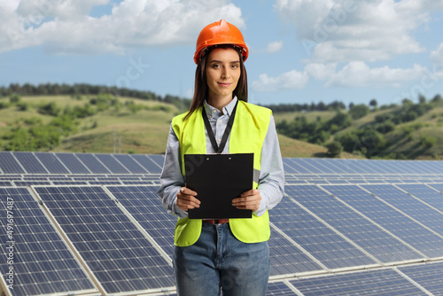 Female engineer holding a clipboard on a photovoltaic solar station
