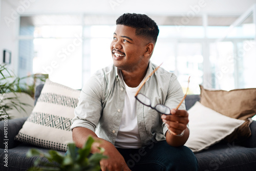 The future is full of potential. Shot of a young businessman sitting on a sofa and looking thoughtful in a modern office.