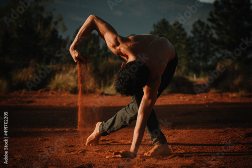 Young dancer performing and playing with red sand ground in the mountains