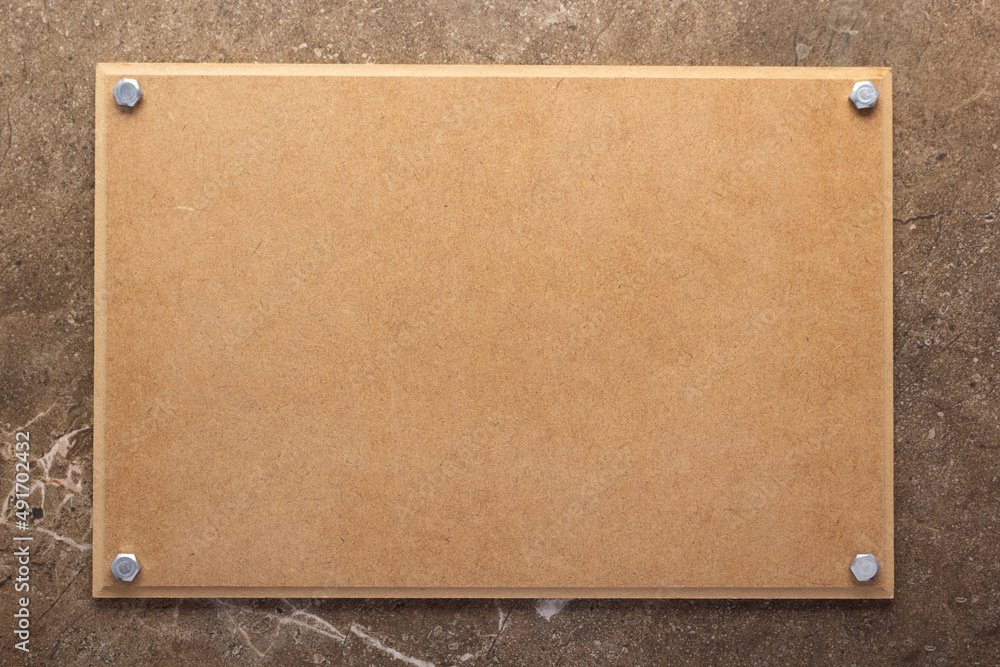 Fototapeta premium Wooden nameplate or sign board screwed on wall background. Front view of name plate