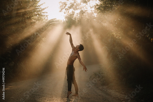 Fototapet Young man doing yoga dance in the nature with a beautiful fog light in the middl
