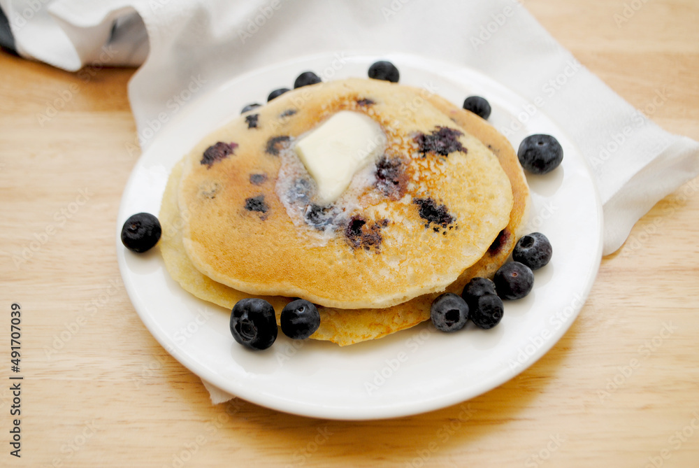 Eating Blueberry Pancakes Covered with Butter 