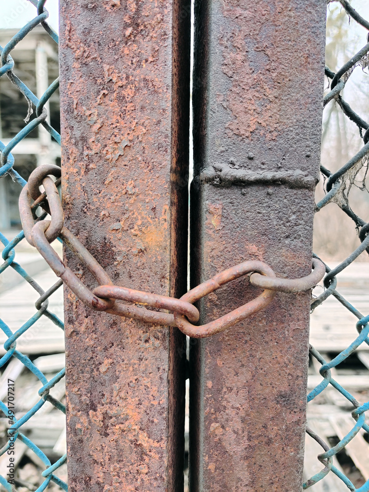 Close-up of a chain hanging on a rusty wire fence Close-up of a chain hanging on a rusty wire fence