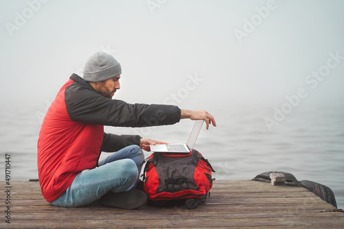 Digital nomad concept. Young man puts laptop over backpack to work