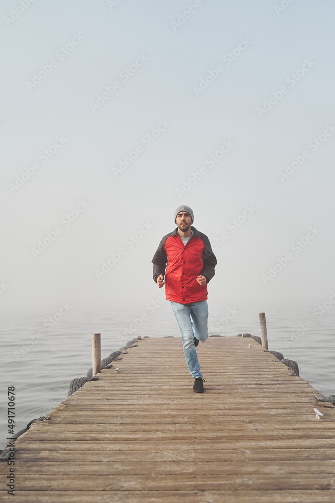 Facing new challenge concept. Young male running by the ocean on wooden dock
