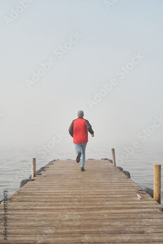 Adventure concept. Young man runs to immense ocean with fog 