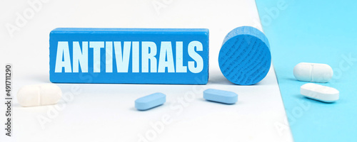 Quadro su tela On a white and blue surface are pills, a pen and a wooden sign with the inscript