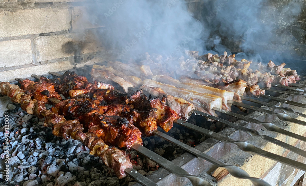 Pork and lamb shashlik in metal skewers on a stone grill Pork and lamb shashlik in metal skewers on a stone grill