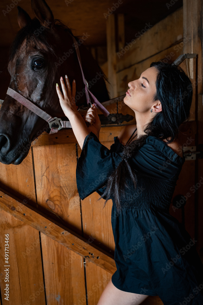 Girl with long black hair in the countryside. Ipadrome with horses. Rural landscapes, wild west.