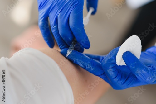 Female doctor making injecting using syringe to male patient in hospital. Senior man taking injection for flu in clinic. Female doctor vaccinating a man.