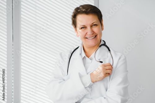 Portrait of middle age female doctor is wearing a white doctor's coat with a stethoscope around her neck.