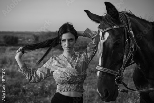 Girl with long black hair in the countryside. Ipadrome with horses. Rural landscapes, wild west.