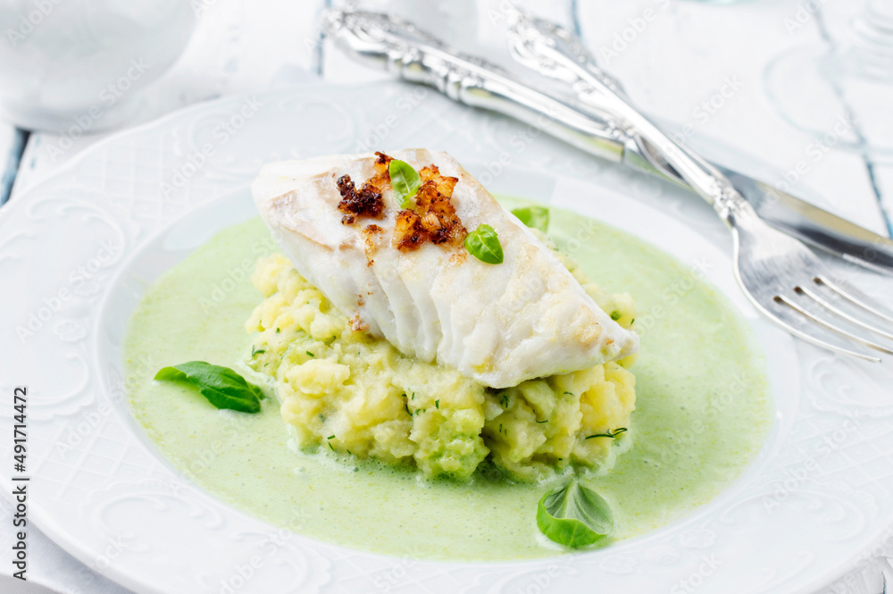 Traditional skrei cod fish filet mashed potatoes in basil champagne foam served as close-up on a classic plate Traditional skrei cod fish filet mashed potatoes in basil champagne foam served as close-up on a classic plate