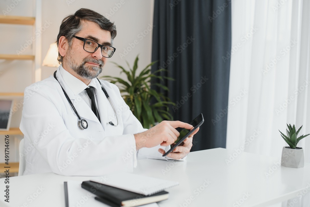 Senior doctor using his tablet computer at work. Senior doctor using his tablet computer at work.