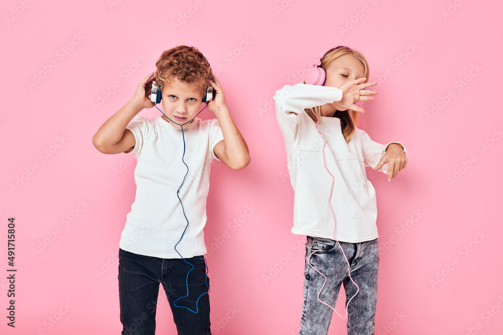 Active young people stand next to in headphones pink color background Active young people stand next to in headphones pink color background