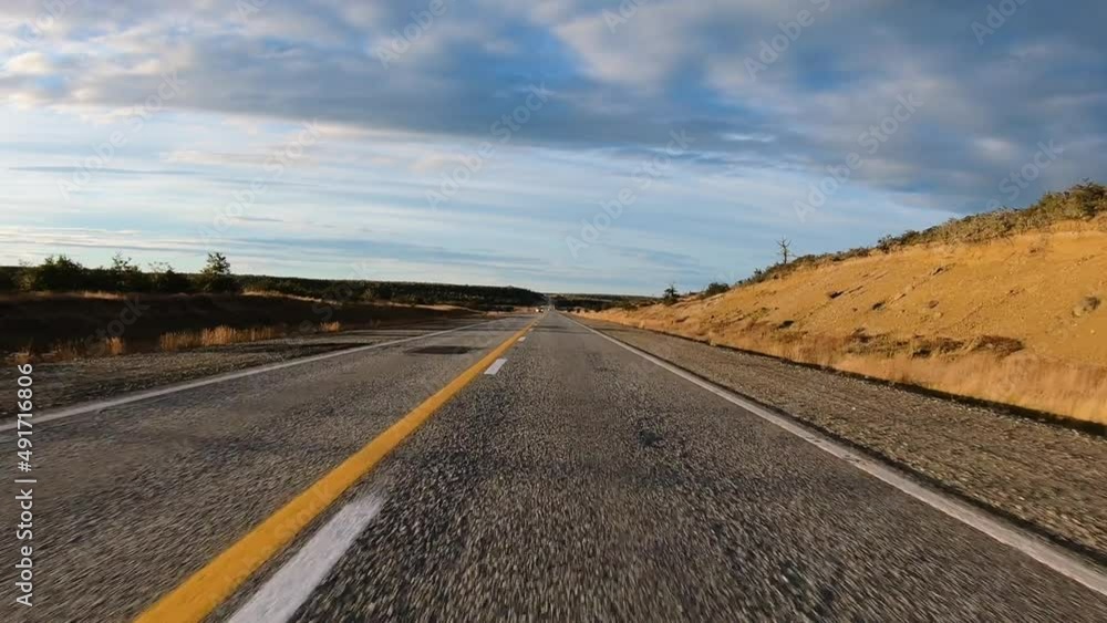 Vehicle shot. Rural road. Point of view of a car speeding the road in the yellow meadow with a beautiful sunset light. Vehicle shot. Rural road. Point of view of a car speeding the road in the yellow meadow with a beautiful sunset light.