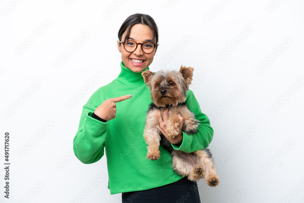 Young hispanic woman holding a dog isolated on white background and pointing it Young hispanic woman holding a dog isolated on white background and pointing it