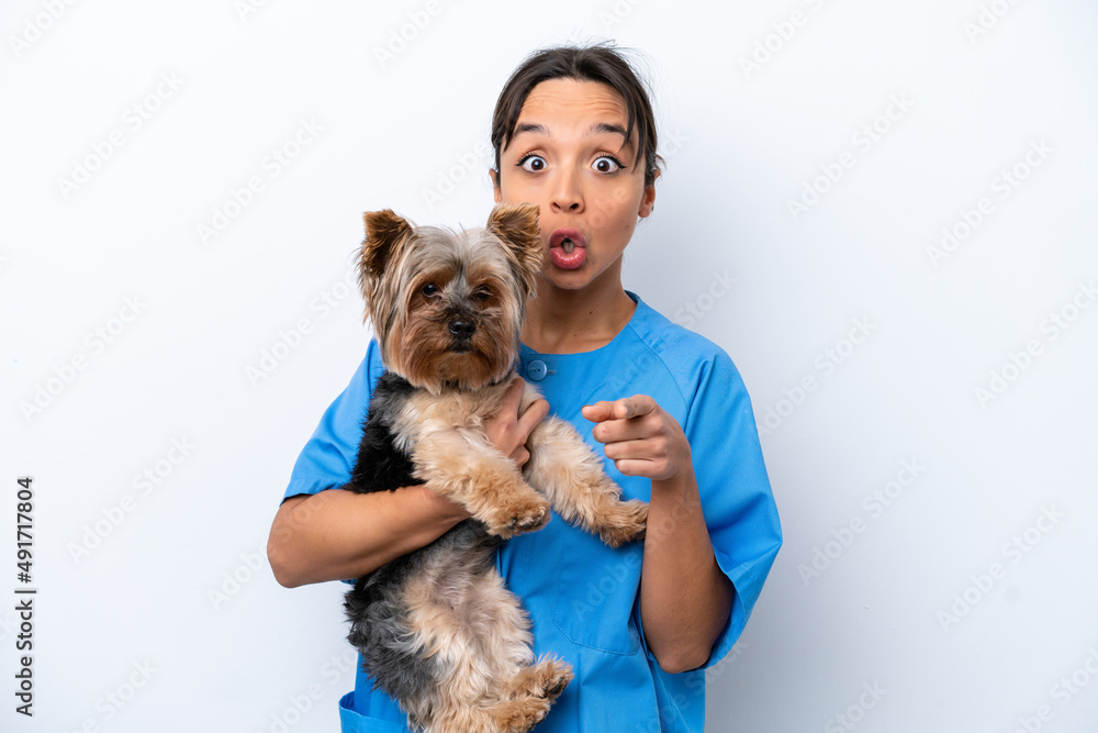 Young veterinarian woman with dog isolated on white background surprised and pointing front Young veterinarian woman with dog isolated on white background surprised and pointing front