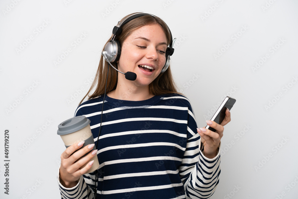 Telemarketer caucasian woman working with a headset isolated on white background holding coffee to take away and a mobile Telemarketer caucasian woman working with a headset isolated on white background holding coffee to take away and a mobile