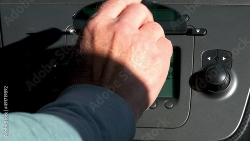 The hand of a man inserts a CD into the car radio. Playing track 1. Using the rotating knob increases the volume. Car stereo. Inside car video. Audio CD.  
 photo