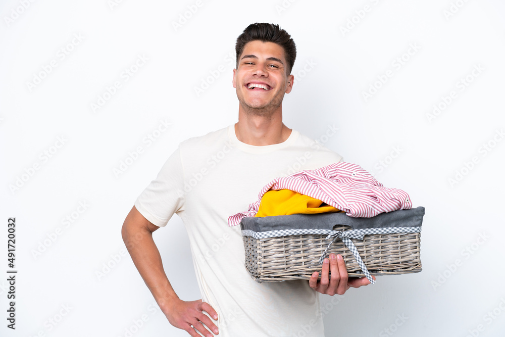 Young caucasian man holding laundry basket isolated on white background posing with arms at hip and smiling Young caucasian man holding laundry basket isolated on white background posing with arms at hip and smiling