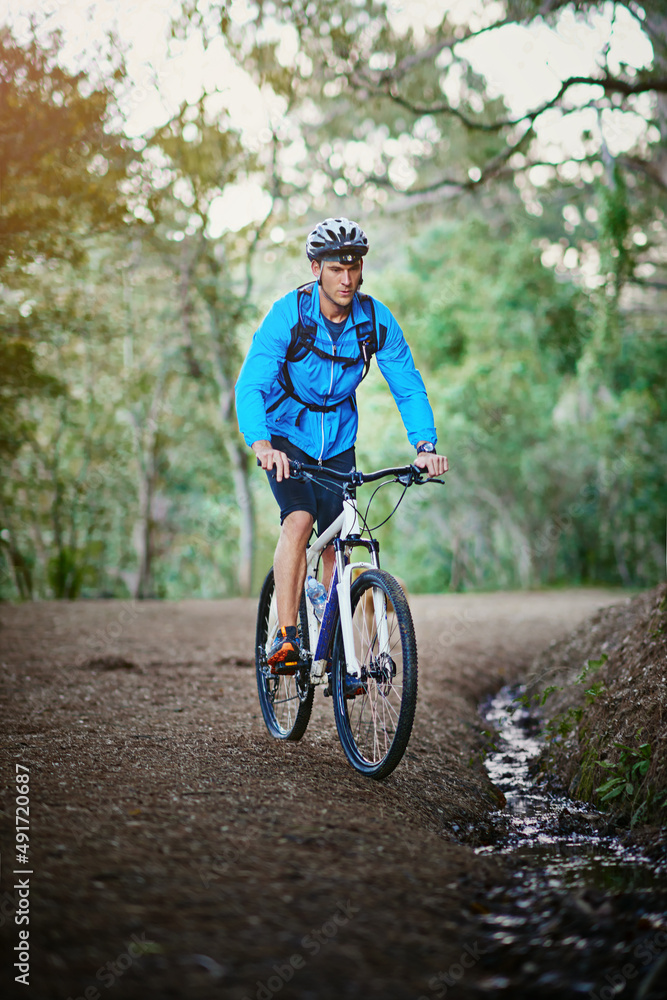 Keeping fit and enjoying nature. Shot of a male cyclist riding along a mountain bike trail.