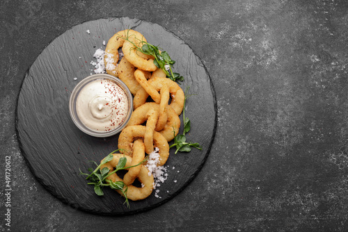 Fotografie Fried squid rings in batter with sauce on stone