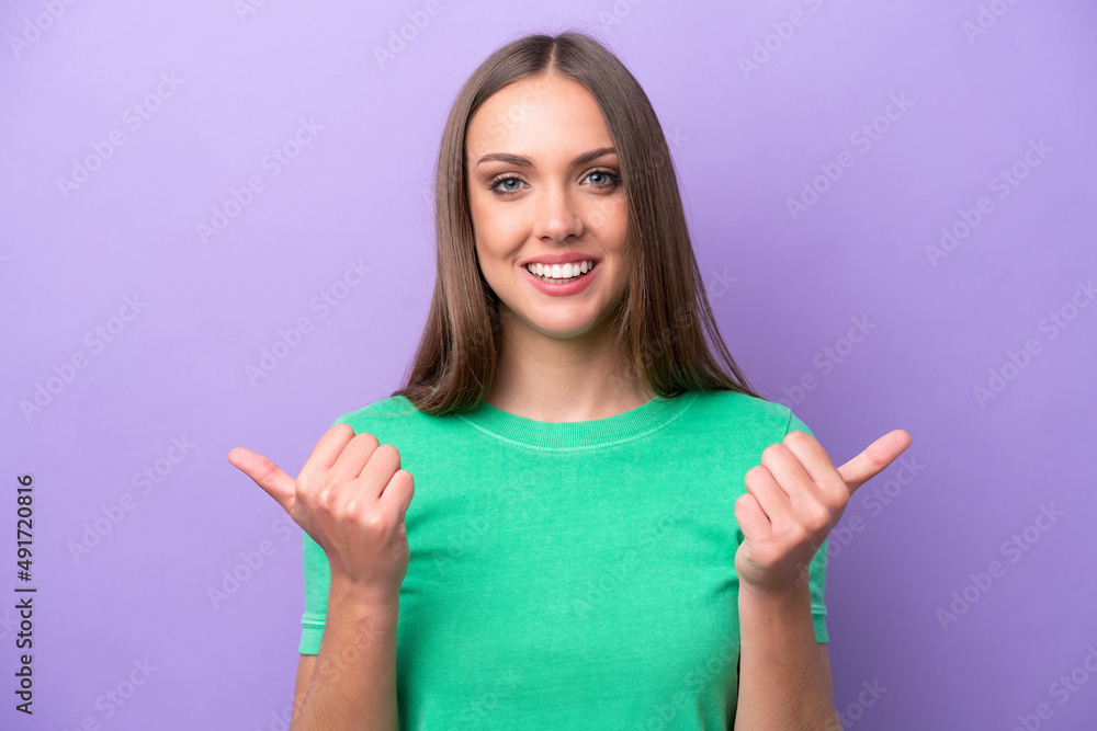 Young caucasian woman isolated on purple background with thumbs up gesture and smiling