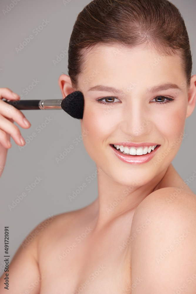 Just a light blush.... Studio shot of a beautiful woman applying blush to her cheeks.