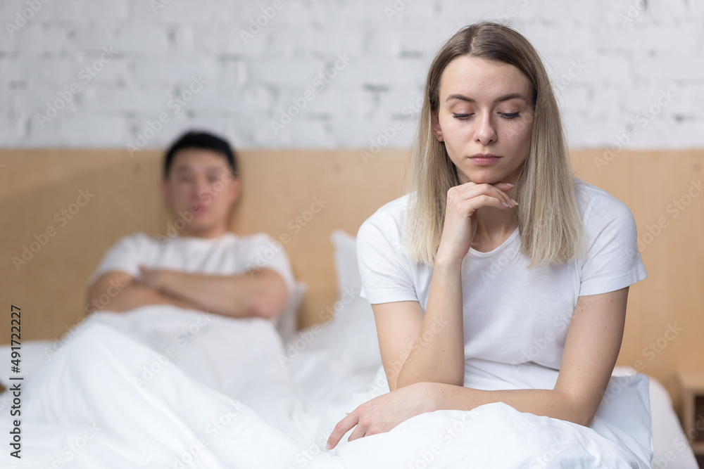 Frustrated woman sitting in bed unhappy asian man, at home, under blanket Frustrated woman sitting in bed unhappy asian man, at home, under blanket