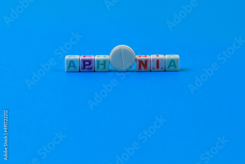 APHONIA text made in cubes, a white medical pill with a score instead of the letter O. Classic blue background photo