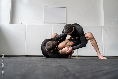 two men brazilian jiu jitsu bjj grappling drill technique or sparring at training at gym academy guard position martial arts copy space