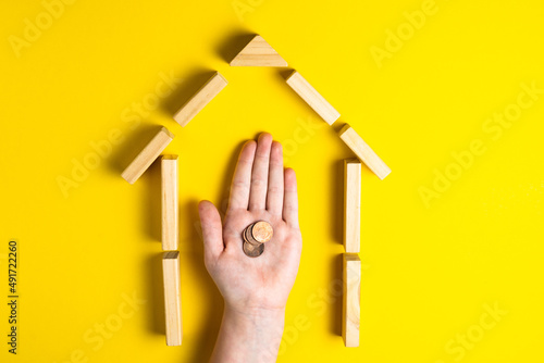 Top view of child's hand close up building blocks showing mince money, house, wooden hut