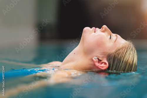 Cool the body, calm the mind. Shot of a young woman relaxing in the pool at a spa.
