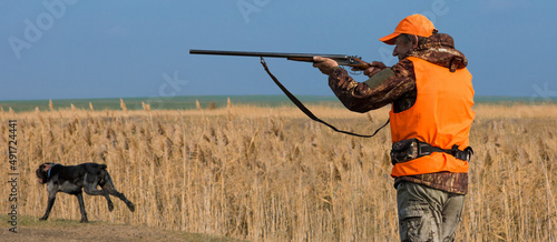 Hunter man in camouflage with a gun during the hunt in search of wild birds or game. Autumn hunting season.