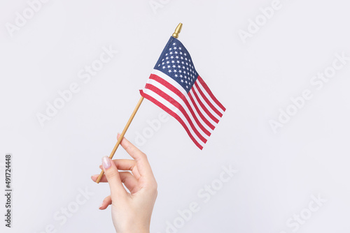 A beautiful female hand holds an American flag on a white background.