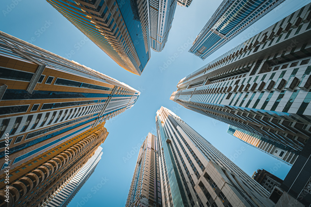 Modern glass skyscrapers in Dubai with blue sky in background. Impressive architecture of financial district and Dubai marina.