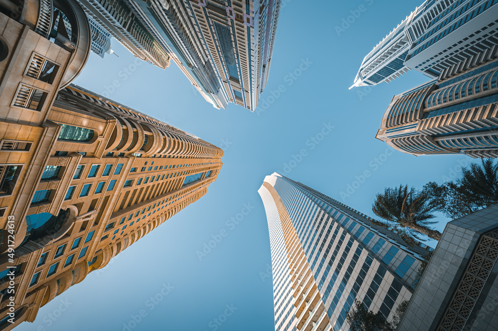 Modern glass skyscrapers in Dubai with blue sky in background. Impressive architecture of financial district and Dubai marina.