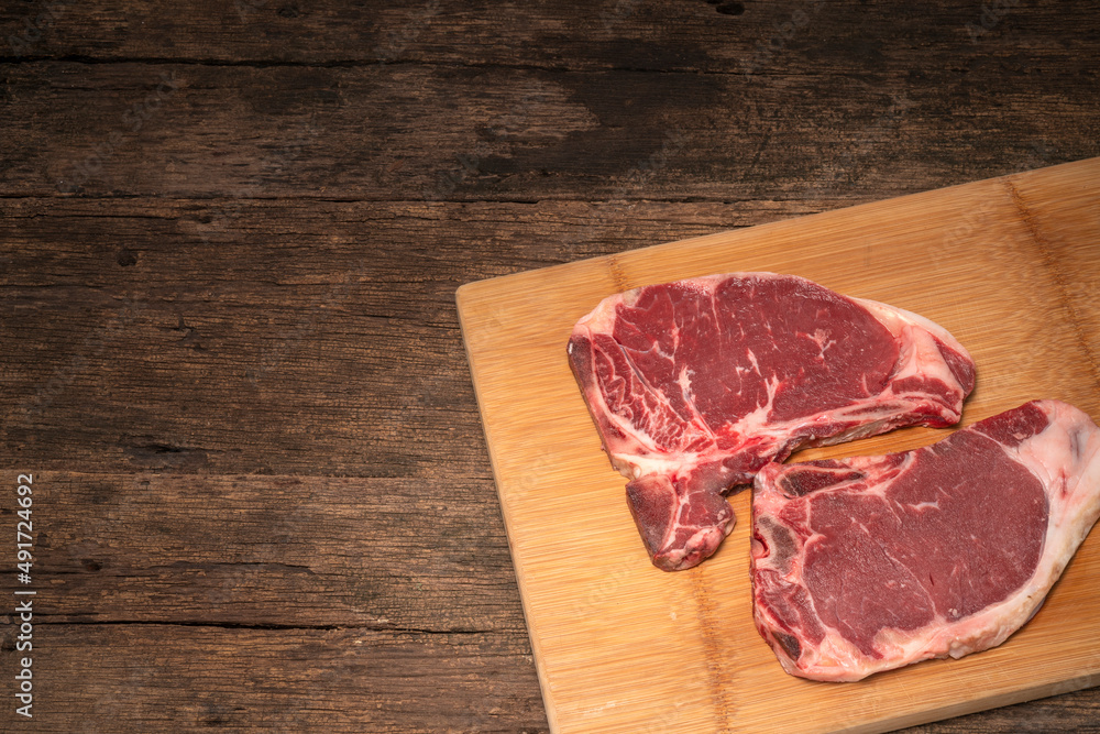 Raw fresh beef T-bone steak on wooden background, Close-up view of marble t-bone steak isolated on wooden background. Raw fresh beef T-bone steak on wooden background, Close-up view of marble t-bone steak isolated on wooden background.