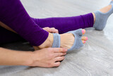 Close up Woman in purple leggings putting on her grey socks. Lady prepare for yoga workout. Concept of yoga accessories 
