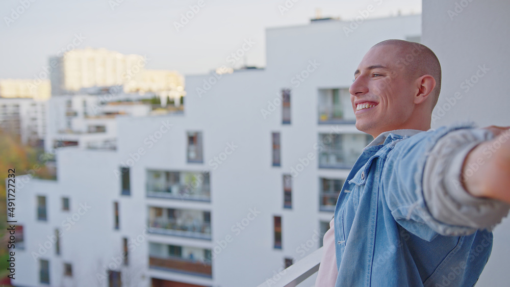 Happy caucasian queer non-binary person standing on balcony and smiling. High quality photo Happy caucasian queer non-binary person standing on balcony and smiling. High quality photo