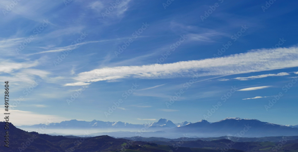 Montagne innevate e vallate nel cielo azzurro in una tersa giornata di sole invernale