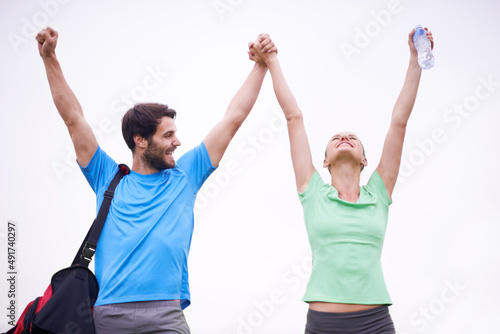 Achieving our fitness goals together. A young couple in sportswear raising their hands in the air as they celebrate a victory.