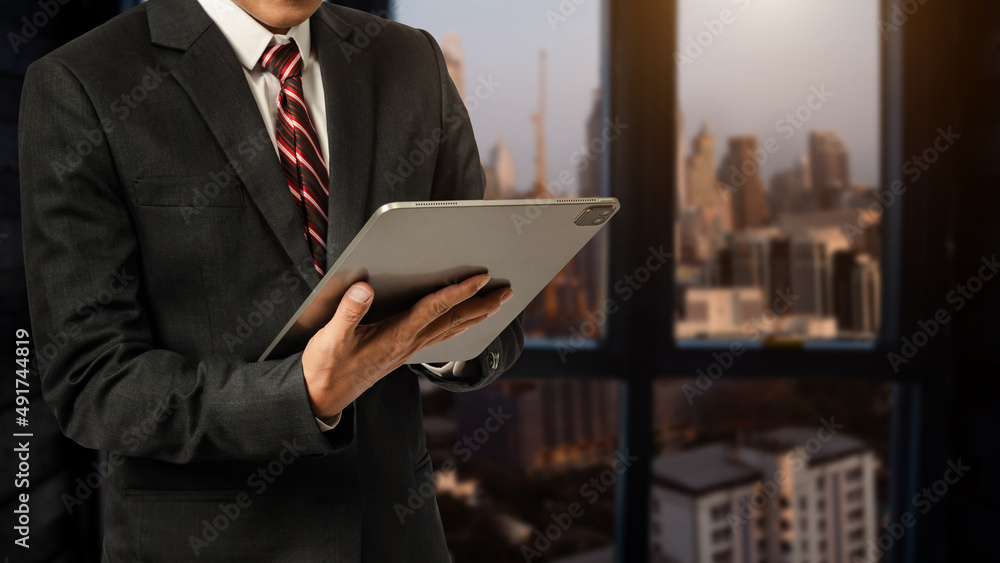 Business man in white shirt using or browsing internet on digital tablet computer with blurred modern office background. Business man in white shirt using or browsing internet on digital tablet computer with blurred modern office background.