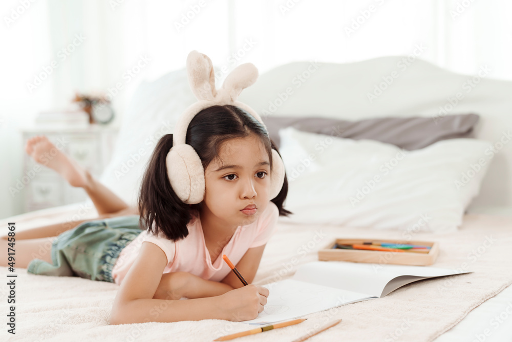 4k 50fps Cute little girl having fun in cute kindergarten age. Use colored pencils to draw a picture on the paper. Happily put the rabbit headphones on the bed. Concept family and happy learning 4k 50fps Cute little girl having fun in cute kindergarten age. Use colored pencils to draw a picture on the paper. Happily put the rabbit headphones on the bed. Concept family and happy learning