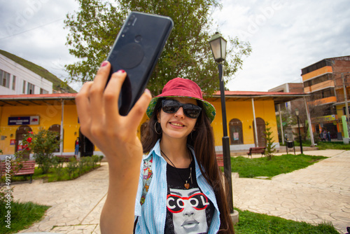 Turista mujer haciéndose una selfie en ciudad pequeña (Sudamérica) photo