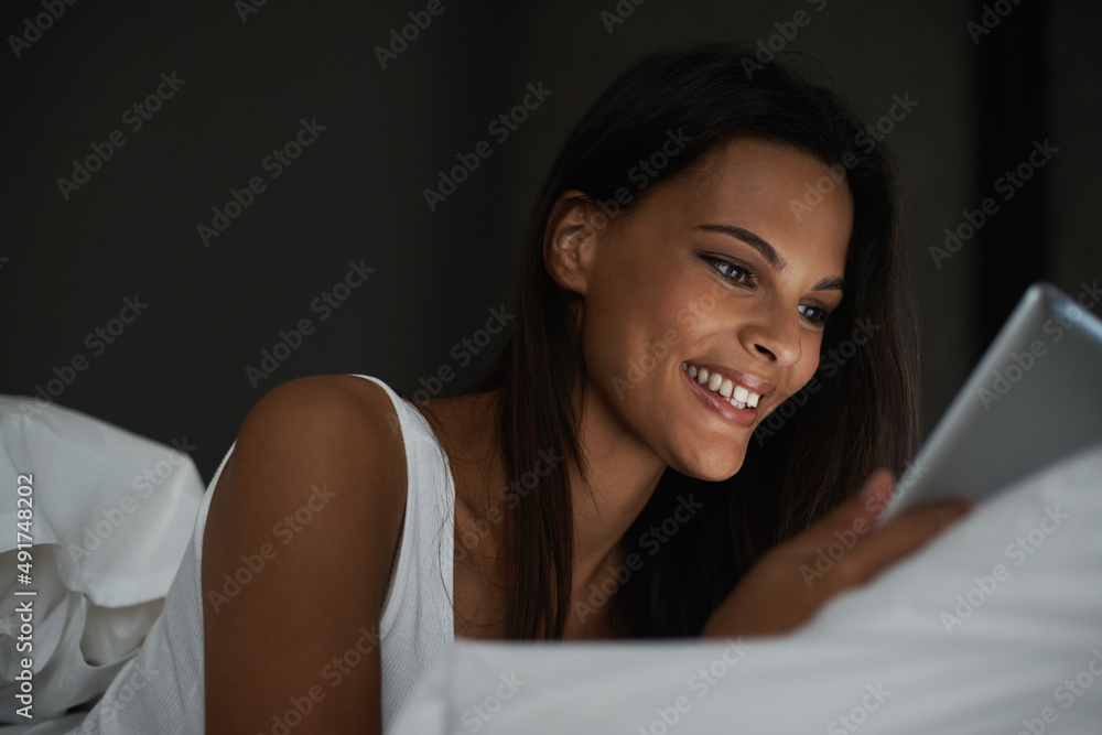Nocturnal social networking. Shot of a beautiful young woman relaxing in bed with her tablet. Nocturnal social networking. Shot of a beautiful young woman relaxing in bed with her tablet.