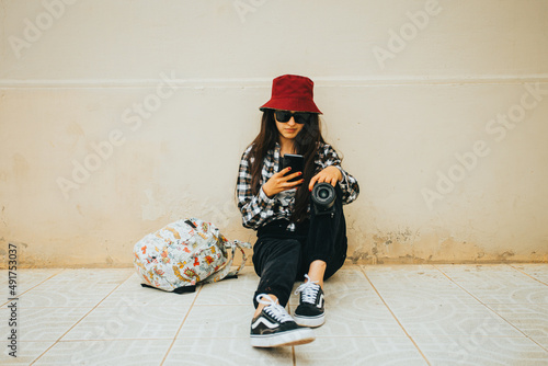 Joven fotógrafa sentada revisando su teléfono móvil photo