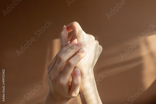 Beautiful female hands apply cream, lotion to skin. Close-up, beige background with striped shadow. Concept of care and beauty photo
