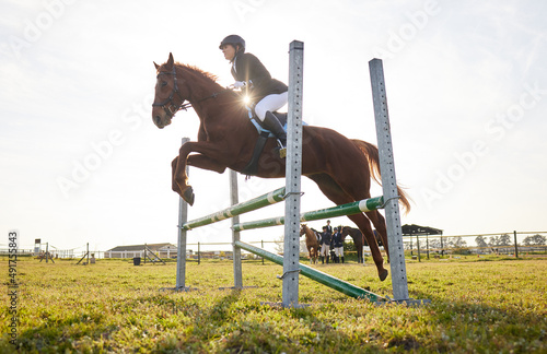 In riding a horse, we borrow freedom. Shot of a young rider jumping over a hurdle on her horse. © Nina L/peopleimages.com